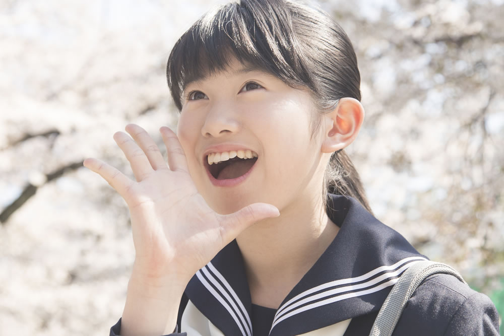 桜の前で笑顔の中学生